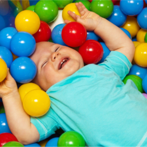 A baby is laying in the ball pit